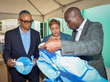 State Minister in the Ministry of Health and Wellness, Krystal Lee (centre) and Chairman, Southern Regional Health Authority (SHRA), Michael Stern (left) look on as United Kingdom (UK)-based Jamaican businessman Branatic Neufville highlights the features o