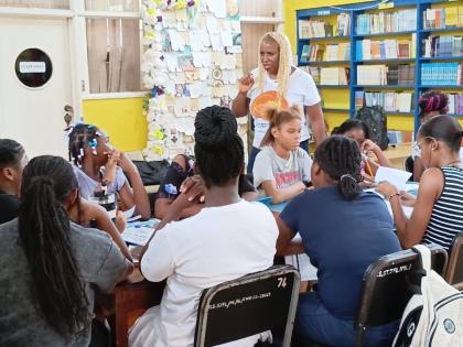 Dr Janice Johnson Dais founder of the GrassROOTS Community Foundation interacting with the girls from Flankersduring one of her literacy empowerment sessions at the St James Parish Library.
