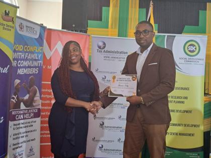 Shanice Kelly (left), one of the beneficiaries of a netball programme instituted by the Social Development Commission (SDC) in Flankers, St James, receives a certificate of participation from Omar Frith, the SDC’s executive director, during the SDC’s i