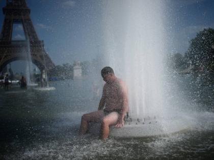 FILE - A person cools off at Trocadero fountain near the Eiffel Tower during a heat wave in Paris, on June 24, 2026. (AP Photo/Christophe Ena, File)