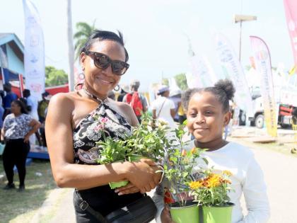 A woman and a young girl display flowers purchased at the Denbigh Agricultural, Industrial and Food Show in Clarendon.