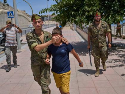 A 12-year-old unaccompanied minor who crossed into Spain is escorted by a Spanish soldier to the Spain-Morocco border from the Spanish enclave of Ceuta, Monday.