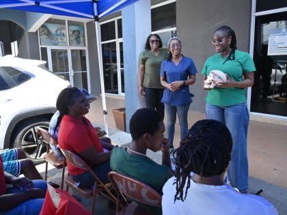 BRIDGING COMMUNITY CARE: Dr. Simone Brady (left), dental surgeon, outlines paediatric oral care to parents and children during D.B.L.’s back-to-school health drive in Portmore on Saturday, August 29. Joining her are visiting physician Dr. Daniella Malco