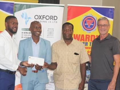 From left: Richard Vernon, mayor of Montego Bay, presents a cheque to Wayne White, a final-year law student, covering $100,000 in scholarship assistance from the Mayor’s Charity Fund. Sharing the occasion are Gregory Harris, councillor for the Salt Sprin