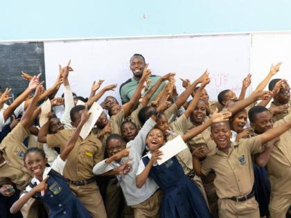 Students share a moment with Olympic champion Usain Bolt after receiving support from the Usain Bolt Foundation.