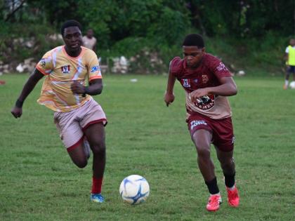 St James High’s Davano Brown (left) and Herbert Morrison Technical High’s Aiden James chase the ball during their ISSA daCosta Cup preliminary round game at Herbert Morrison playing field yesterday. St James won 3-2.
