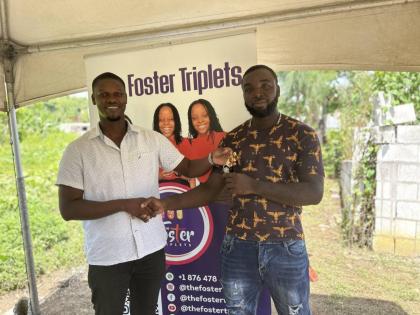 Teejae White (left), a representative of the Foster Triplets Ministries, hands over the keys to Damion Farquarson (right) as he is welcomed to his new home.