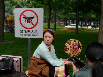 A performer rests near a “No Drone Zone” sign in Beijing, on May 31, 2023. 