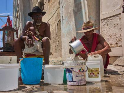Oscar Joaquín López (left) and his housemate Wilfredo Cisneros Duarte collect water from a street pipe in Havana, Cuba, on September 7.