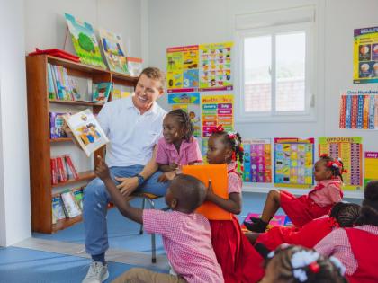 Executive Chairman Sandals Resorts and President Sandals Foundation, Adam Stewart reads to students of Culloden Infant inside newly constructed school library provided and resourced by the Sandals Foundation.