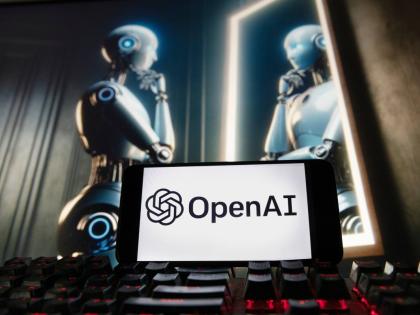 The OpenAI logo is displayed on a cell phone with an image on a computer monitor generated by ChatGPT's Dall-E text-to-image model on December 8, 2023 in Boston.  AP 