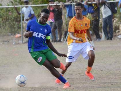 Demarco Hunter (left)  of Norman Manley High shields the ball from Malachi Matthews of Donald Quarrie High during their ISSA Manning Cup match at Maxfield Park yesterday.