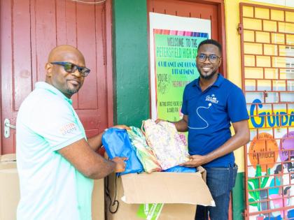 Omar Wright, lead, environment and community development, at the JN Foundation, hands over back-to-school-supplies to Roan Green, principal of Petersfield High School in Westmoreland. The JN Foundation made the donation to the institution during a visit to