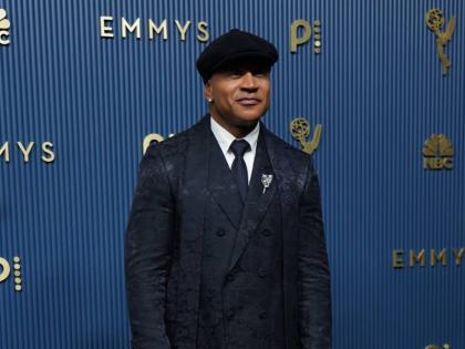 LL Cool J keeps things classic with a twist, stepping onto the Emmy carpet in a dark, patterned double-breasted suit, matching tie, and flat cap. A statement brooch and polished accessories completes the look.