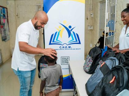 C.H.E.W. Foundation CEO, Sereste Bell (left) presents a backpack filled with school supplies to a participant of SOS Children’s Villages Jamaica. Looking on is the foundation’s chairperson, Dr Leanne Levers.