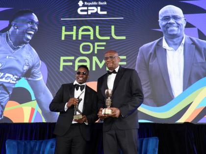 Dwayne Bravo (left) and Ian Bishop display the trophies they earned during a Caribbean Premier League Hall of Fame induction ceremony at the Hilton Barbados on Tuesday.  
