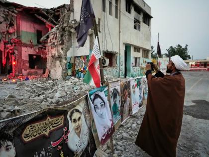 A cleric takes a photograph at the shattered Shajareh Tayyebeh school, which has become a place of mourning and a memorial to those killed in a US airstrike on February 28, in Minab, southern Iran, September 7.