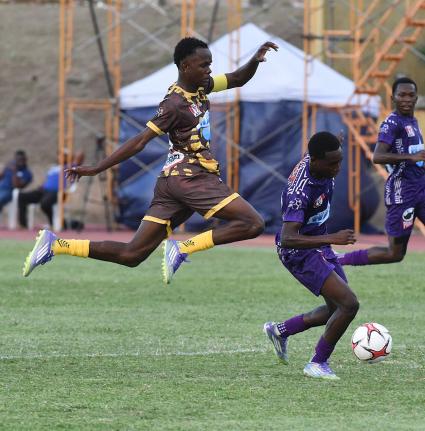 Andre Langford (left) of Charlie Smith High moves to tackle Kajay Fletcher of Kingston College during their Manning Cup football match at the Stadium East field last Saturday.