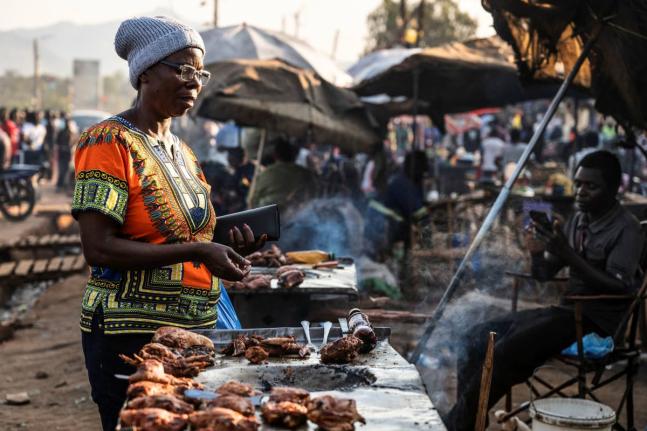 A woman buys food from a street vendor in Zomba, Malawi.