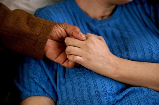 This image provided by News21 shows Junior Clase and his wife, Solibel Olaverria, holding hands on Sunday, June 22, 2025, at Olaverria's rehabilitation facility in Allentown, Pa. (Jessica Sachs/News21 via AP)