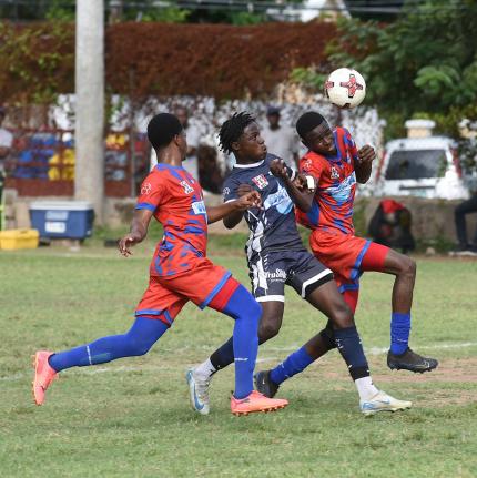 Ian Allen/Photographer 
Jamaica College’s (JC) Dwayne Burgher (centre) tries to get between Camperdown’s Roberto Menzie (left) and Nathaniel Grappie during their ISSA/WATA daCosta Cup football match at the Alpha Boys playing field yesterday. JC won 2-0