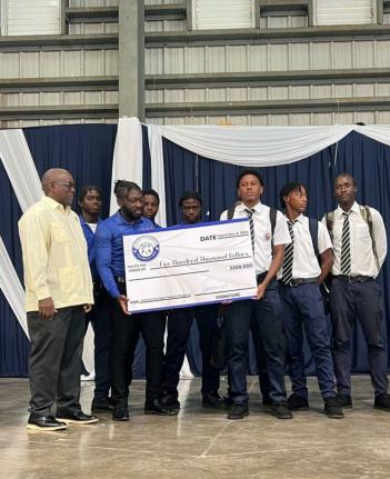 
From left: Jamaica College principal, Wayne Robinson, helps Manning Cup players Joshua King, Devonte Allen, Dontae Logan (captain holding cheque), Duwayne Burgher, Delajahe McCormack and Domanic Clarke (also holding cheque), and David Simmonds display a s