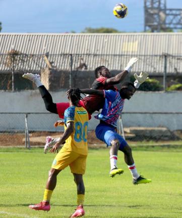 Racing United goalkeeper Aaron Enill jumps to intercept a cross ahead of Portmore United striker Peter McGregor at Ferdi Neita Sports Complex yesterday. Looking on is Jevon Bascow.
