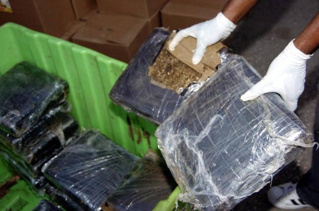 Police examine over 220 packets of compressed ganja prepared for export.