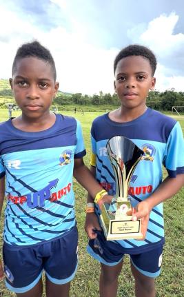 Jasean Anderson (left) and Aamir Witter, co-captains of El Instituto de Mandevilla, display the Youth Football League Junior Cup Under-11 Rural Competition trophy they won at the Kirkvine Sports Complex in Mandeville on Saturday.  