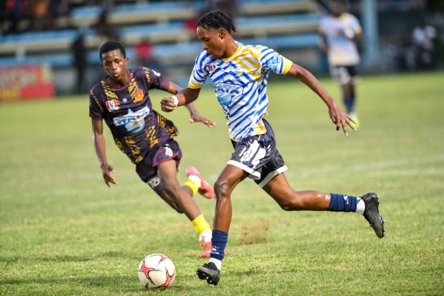Jamaica College’s Malique Bucknor (right) drives the ball forward while being chased by St Andrew Technical High School’s Shankeno Grant during their ISSA/WATA Manning Cup clash at the Drewsland Stadium on September 27.