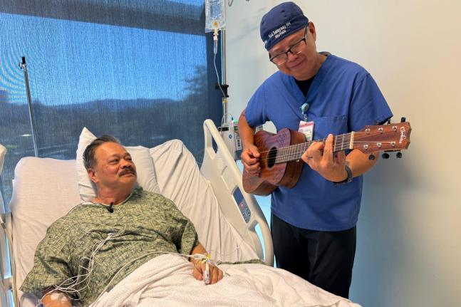 Nurse Rod Salaysay plays guitar for patient Richard Hoang in the recovery unit of UC San Diego Health in San Diego, California, on September 30, 2025. 