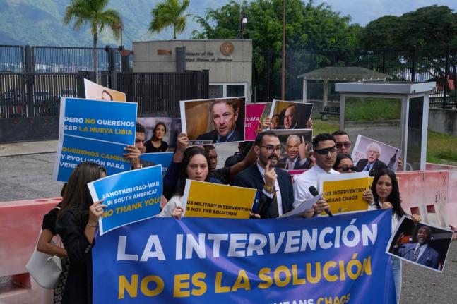 Gabriel Cabrera, president of the Venezuelan Youth Center for Democracy, gives a statement outside of the United States embassy with members of the organisation holding signs that read in Spanish “Intervention is not the solution”, in reference to US w