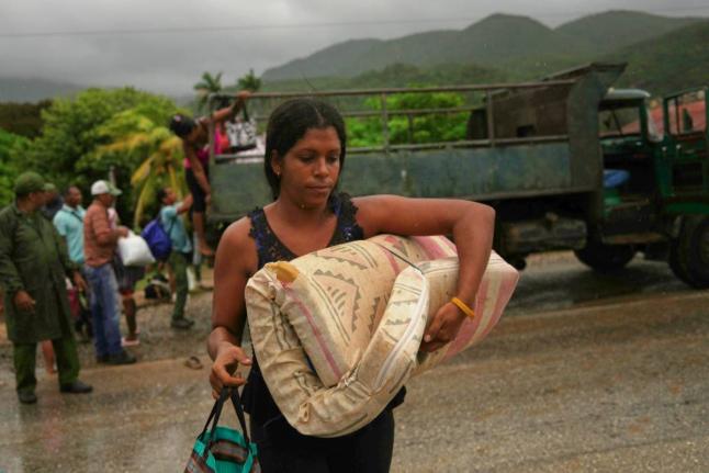 A woman carrying a mattress in the rain evacuates before the arrival of Hurricane Melissa in Cañizo, a community in Santiago de Cuba, Tuesday, October 28, 2025. (AP Photo/Ramon Espinosa)