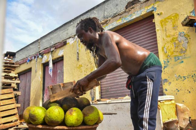 Eyan Williams, resident of Kidd Lane in Kingston, roasts breadfruit for himself and fellow residents after produce fall from trees during onslaught of Hurricane Melissa.