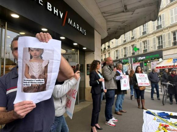 A protester holds a picture of a childlike sex doll outside BHV Marais department store in Parish, Monday, November 3, 2025, where Shein is due to open its first permanent physical store worldwide. (AP Photo/Nicholas Garriga)