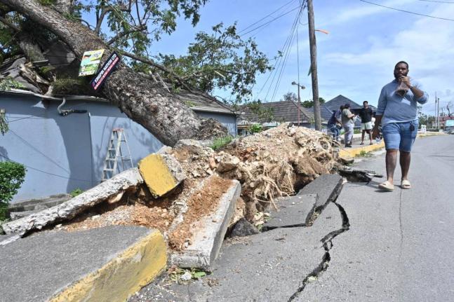 A man walks past a business place in St Ann which was damaged by an uprooted tree during Hurricane Melissa.