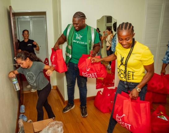 Shelly-Ann Fraser Pryce, founder and head of the Pocket Rocket Foundation, and Alrick Johnson (centre), Logistics Lead for GroceryList Jamaica, gather care packages for distribution in areas affected by Hurricane Melissa.