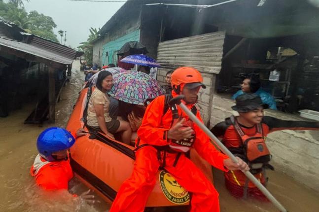 In this photo released by the Indonesian National Search and Rescue Agency (BASARNAS), rescuers on a rubber boat evacuate residents from their flooded home in North Sumatra province, Indonesia Tuesday, November 25, 2025. (BASARNAS via AP)