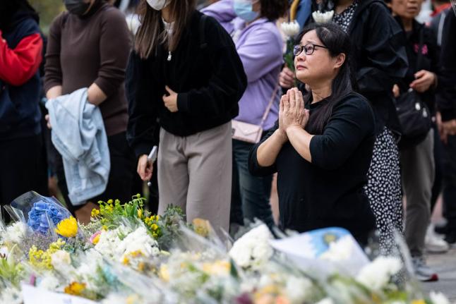 People offer flowers and pray for the victims near the site of a deadly fire at Wang Fuk Court, a residential estate in the Tai Po district of Hong Kong’s New Territories.