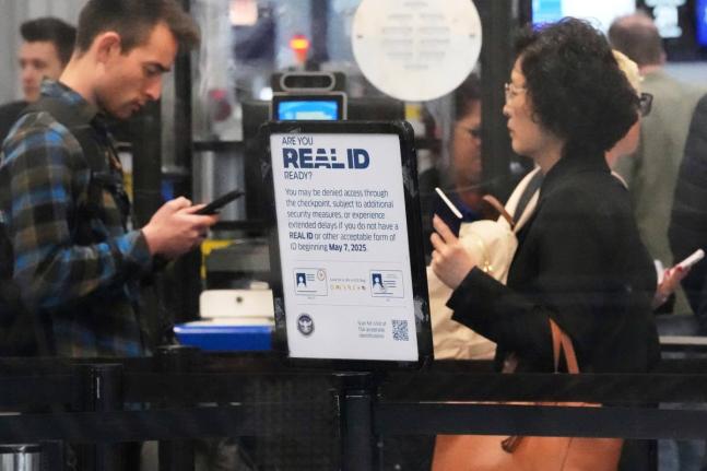 A Real ID sign is displayed as travellers wait to go through security check point at O'Hare International Airport in Chicago, May 23, 2025. (AP Photo/Nam Y. Huh, File)