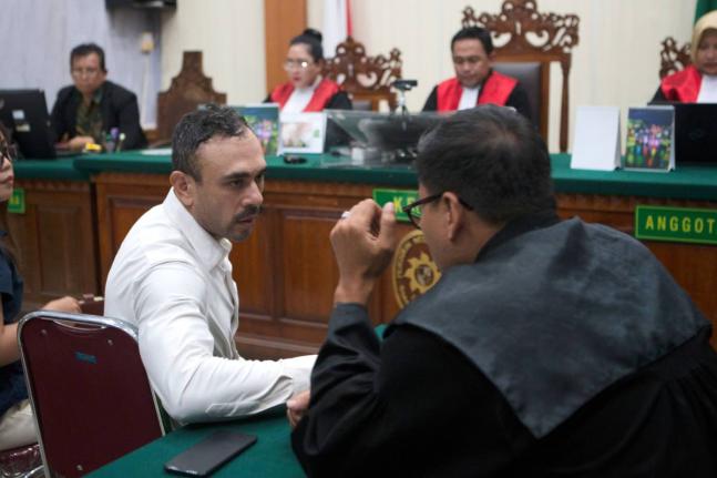 Australian national Lamar Ahchee, left, who is on trial on accusation of attempting to smuggle cocaine into Indonesia, talks to his lawyer during his sentencing hearing at the district court in Denpasar, Bali, Indonesia on December 18, 2025. 