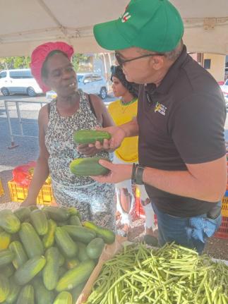 Dr Christopher Tufton, Member of Parliament for St Catherine West Central, speaks with vendor Annmarie Reid about cucumbers during the Green Acres Farmer’s Market in St Catherine on December 22, 2025. 
