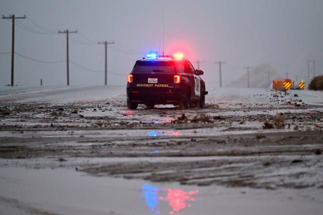 A California Highway Patrol officer drives along California State Route 138 through mud Wednesday, December 24, 2025, near Wrightwood, California. (AP Photo/Wally Skalij)