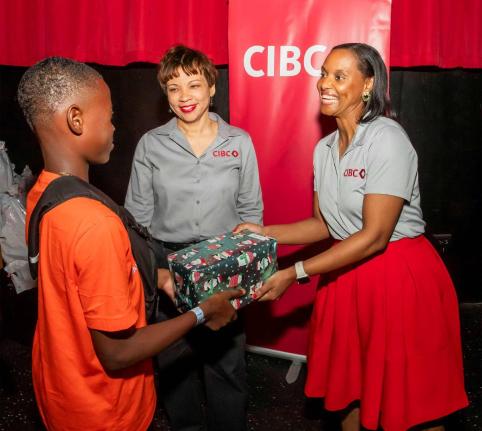 CIBC Caribbean’s Head of Country, Annique Dawkins and Sherian McDonald, senior manager deals management, present gifts to a ward of the state at the United Way of Jamaica’s annual ‘Bringing Cheer to Children in State Care’ initiative.