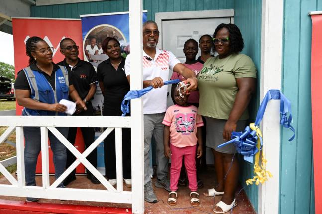VM Group Chairman Michael McMorris (centre) cuts the ribbon to officially hand over a new two-bedroom home to Novia Russell (right) and her children (second to fourth right) Javon, Danique and Zaliyah. Also present are (from left) Kivette Silvera, executiv