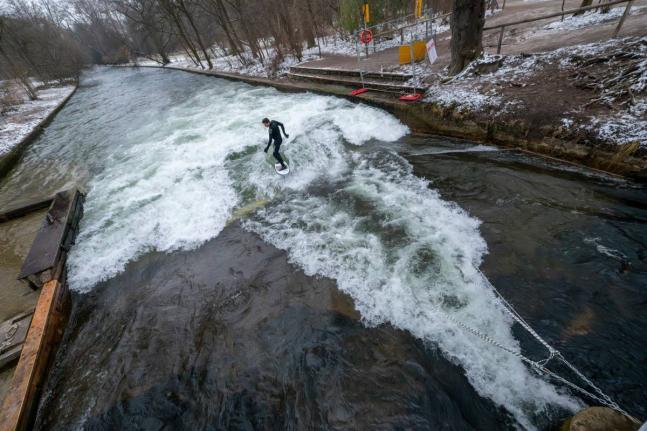 A man tries out the temporary Eisbach wave in the English Garden in Munich, Germany.