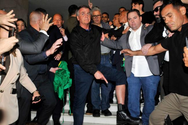 Brazil’s former President Jair Bolsonaro points to his electronic ankle monitor that the Supreme Court ordered him to wear, at Congress in Brasilia.