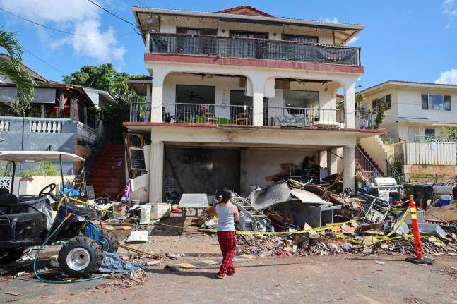  A woman stands in front of the home where a New Year's Eve firework explosion killed and injured people, January 1, 2025, in Honolulu. (AP Photo/Marco Garcia, File)