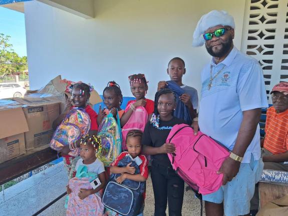  Dr Bevan Earle, more popularly known as ‘The Dukeof Earle’, presenting school bags to children during his 39th annual Christmas Day treat at the Barrett Town Police Station in St James.