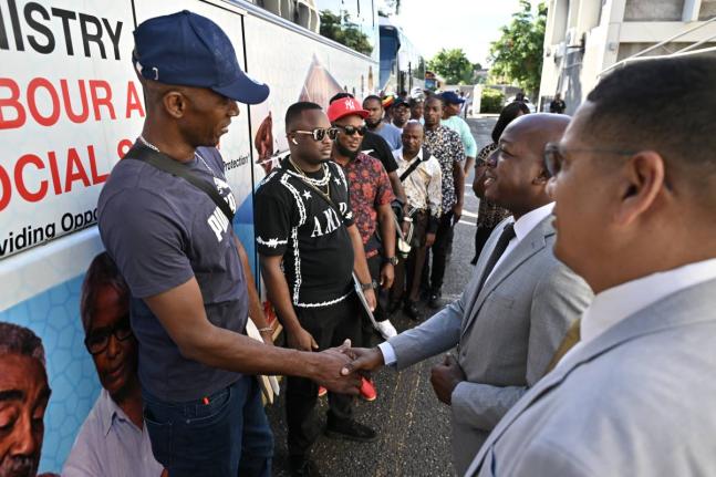 Pearnel Charles Jr, (second right) Minister of Labour  and Social Security, and Donovan Williams, (right) minister of state in the Ministry of Labour and Social Security of Jamaica, greet farm workers at the first send-off ceremony of farm workers to Canad